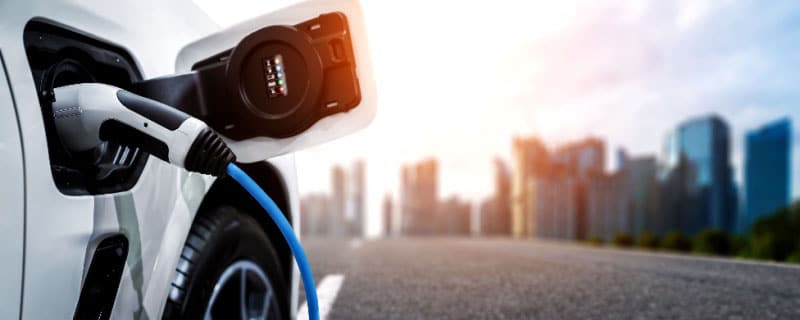 an electric vehicle charging port with a blurred cityscape background.