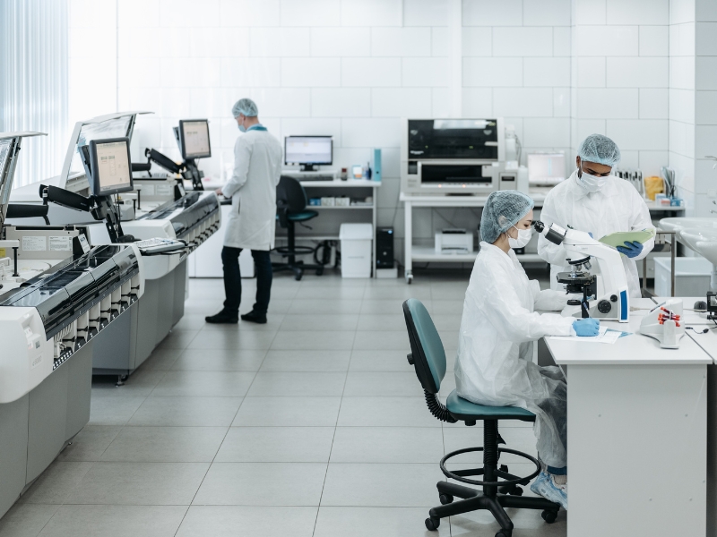 Photo of three cleanroom workers engaged in various tasks.